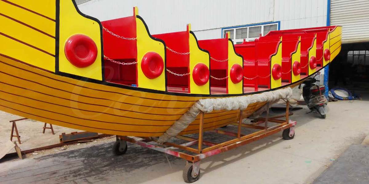 Fiberglass body of 16 seat pirate ship amusement ride with red and yellow seats during production