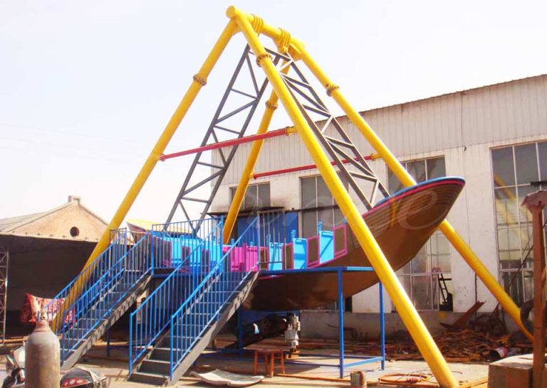 Outdoor operation of 16 seat pirate ship amusement ride with passengers enjoying the swing