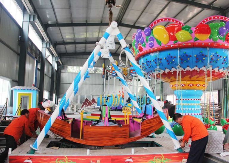 Assembly of a mini pirate ship ride with vibrant decorations for children’s amusement parks.