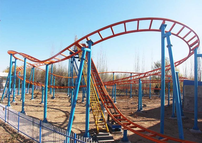 Wide view of family roller coaster track with turns and drops at amusement park.