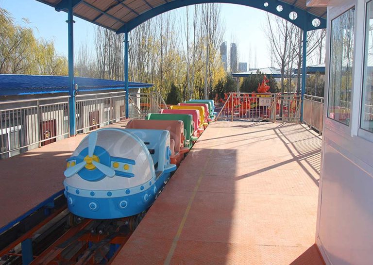 Family roller coaster train with colorful cabins for family and kids ride at amusement park.