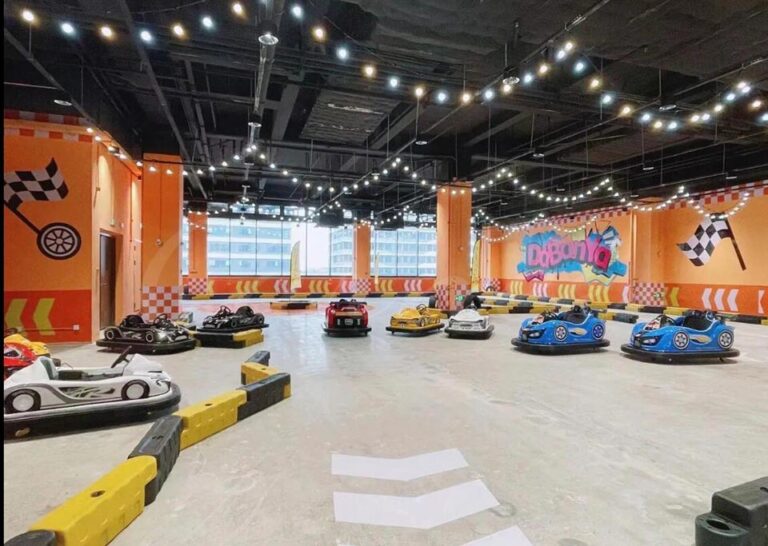 Colorful battery bumper cars lined up at a portable indoor racing track.