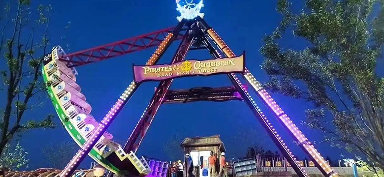 Night-time view of the Pirates of the Caribbean pirate ship ride illuminated with colorful lights, creating an exciting visual appeal