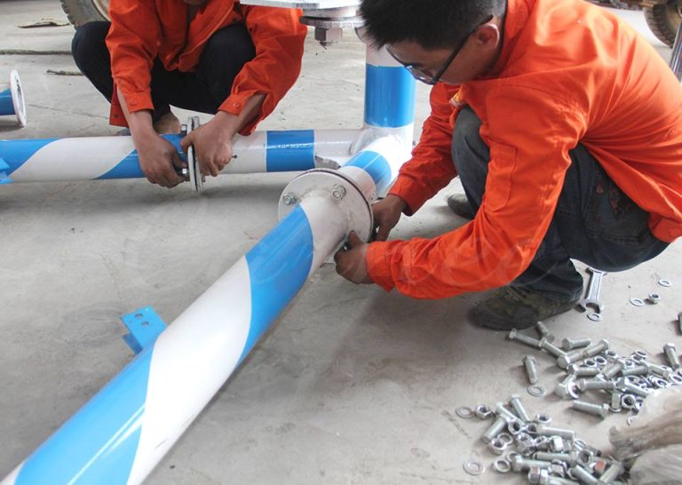Workers installing steel frame structure of 12 seat mini pirate ship ride in factory workshop