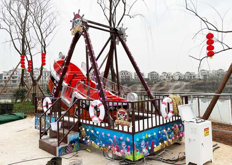 Mini Pirate Ship Ride with safety bars, LED lights, and an ocean-themed base at amusement park.