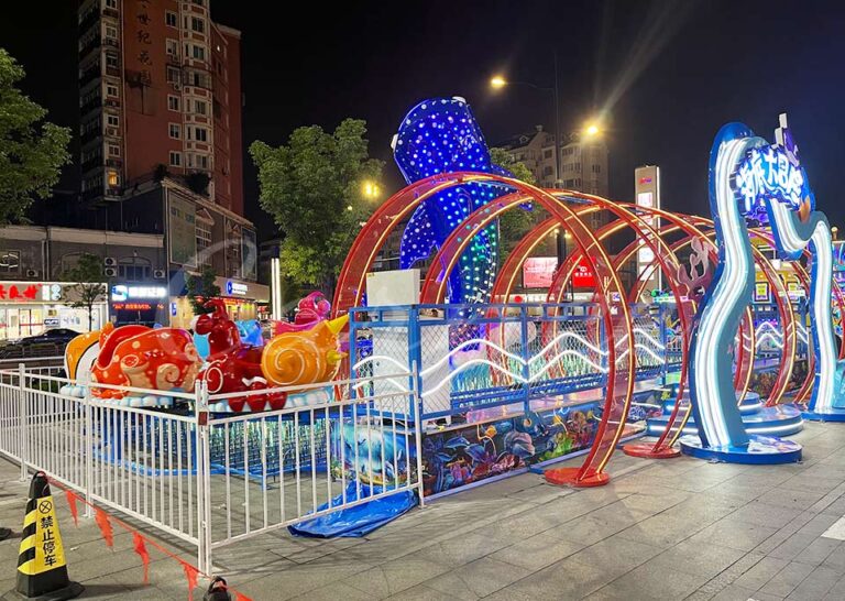 Outdoor family amusement park ride featuring an ocean animal mini roller coaster with bright LED track lighting