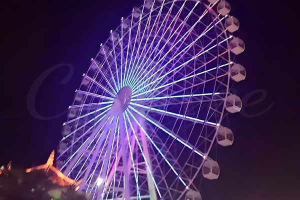 Ferris wheel illuminated with vibrant LED lights at night, offering a stunning view and scenic ride.