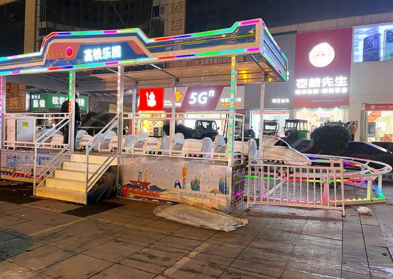 High-speed train park ride with colorful LED lights at night.