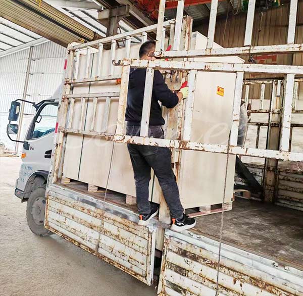 Worker safely loading the mechanical bull wooden crate onto a delivery truck for global transport.