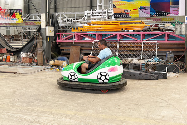 Brazil client experiences LED soccer-themed bumper car during visit to Carnee Rides production workshop.