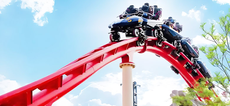 Red steel roller coaster train on a steep curved drop, demonstrating modern roller coaster construction and thrilling ride experience.