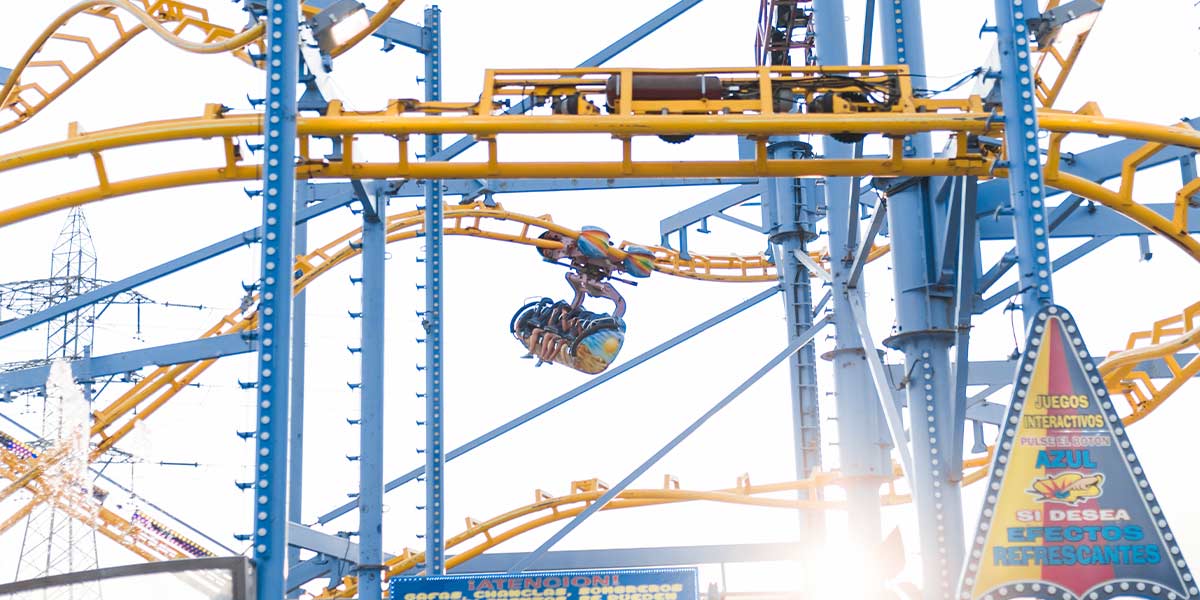 Spinning steel roller coaster with bright yellow tracks, showing complex coaster construction and dynamic ride engineering.