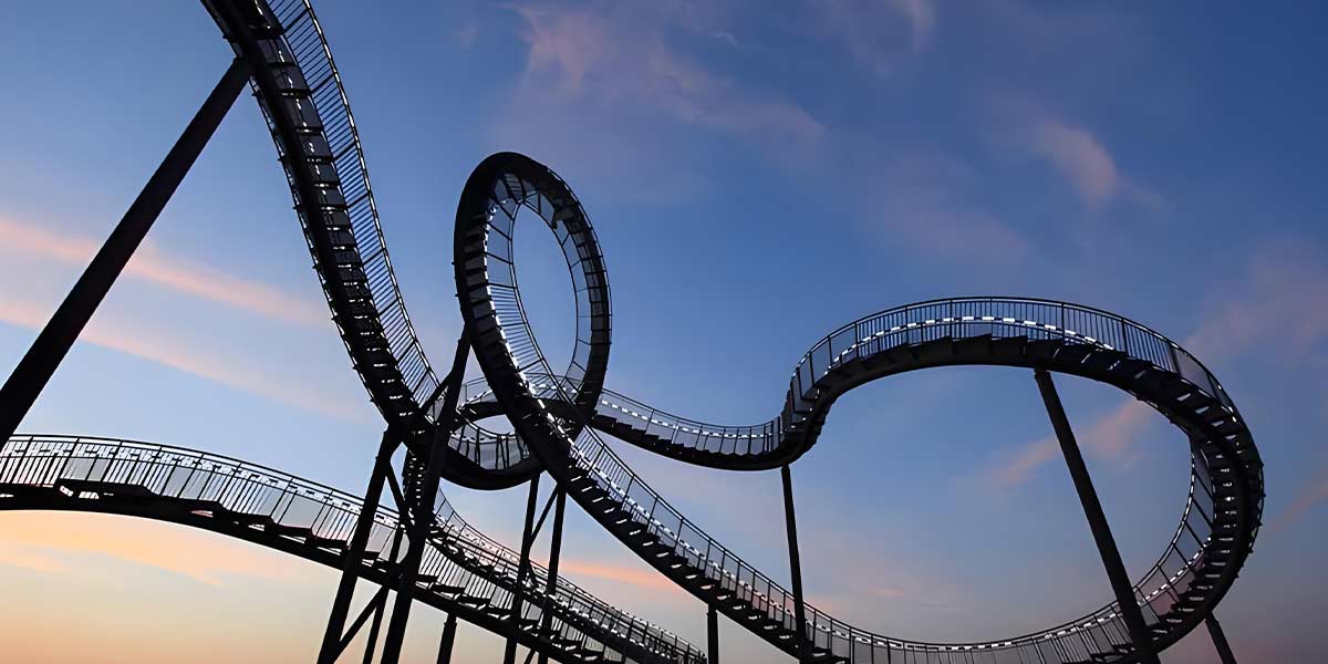 Steel roller coaster track with loops and inversions silhouetted against the sky, highlighting advanced roller coaster build techniques.