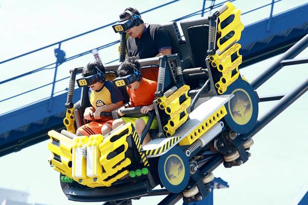 Family enjoying a virtual reality roller coaster ride with themed cars and VR headsets, creating an immersive amusement park experience.