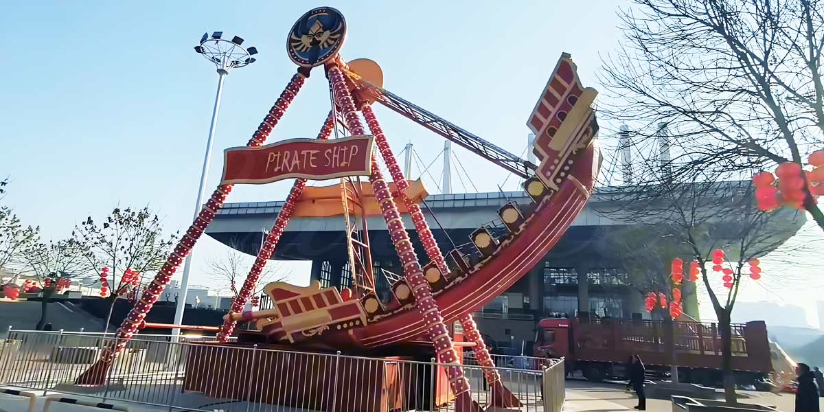 Red CARNEE pirate ship amusement ride installed in China park with festive decoration.