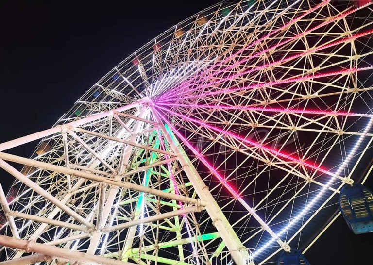 Daytime view of a 49-meter Ferris wheel in operation, with passengers enjoying panoramic views in a bustling amusement park.