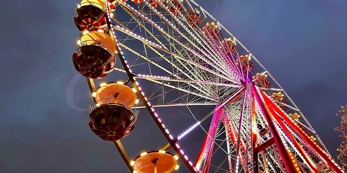 A giant observation wheel with panoramic glass cabins, offering an unobstructed view of the city skyline at sunset.