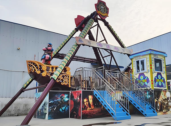 Colorful pirate ship amusement ride with decorated control cabin and passenger seats.