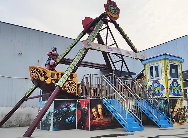 Colorful pirate ship amusement ride with decorated control cabin and passenger seats.