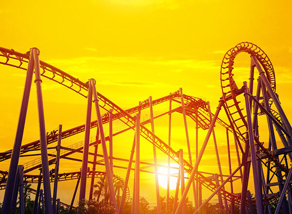 Roller coaster looping track at sunset with orange sky background