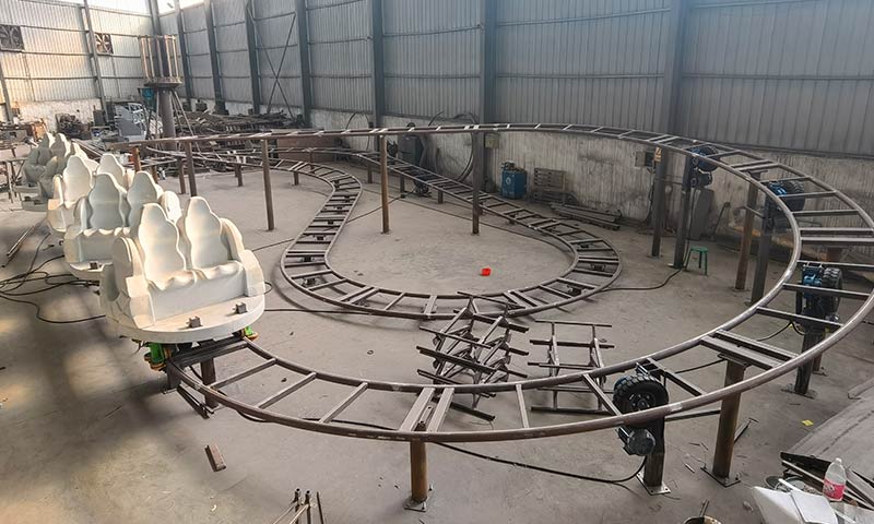 Roller coaster track assembly in progress, showcasing a partially completed track layout and seat installation for a smooth ride experience.