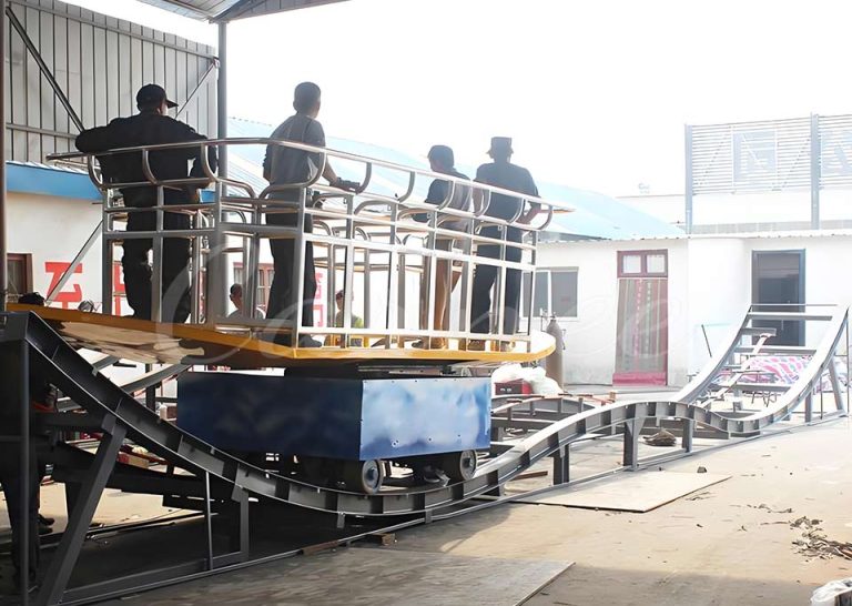 Surf’s Up Ride factory testing stage showing passengers standing on surfboard-shaped gondola along wavy track.