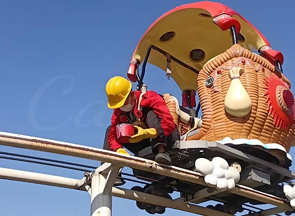 Amusement park ride maintenance worker repairing track with a cup in hand.