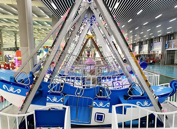 Детский мини-аттракцион "Качели-корабль", установленный в торговом центре, оформлен разноцветными огнями и безопасными элементами для детских развлечений.