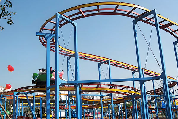 Family backyard roller coaster with colorful rainbow-style steel track and cartoon cars