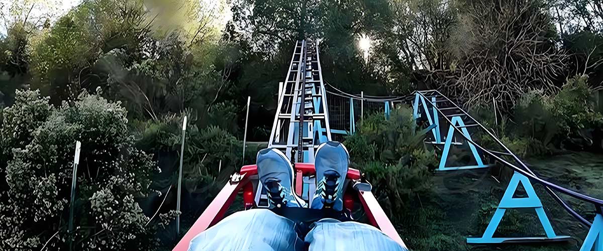 Homemade backyard roller coaster rider view going up a steel track in the woods