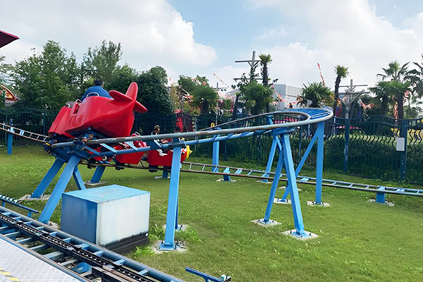 Backyard roller coaster for kids with red airplane-shaped cars on blue steel track