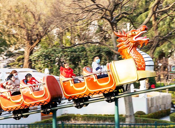 Kids riding a dragon-themed children’s roller coaster in amusement park