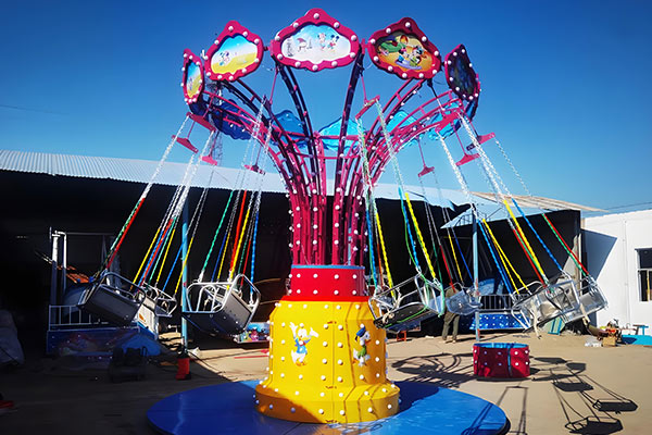 Enfants profitant d'un petit tour de balançoire dans un parc d'attractions, avec des couleurs vives et un design amusant.
