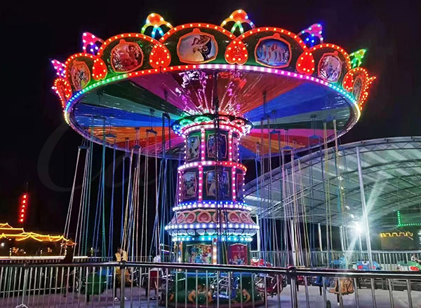 Vintage-style carnival swing ride with bright lights, representing the historical evolution of swing carnival rides.