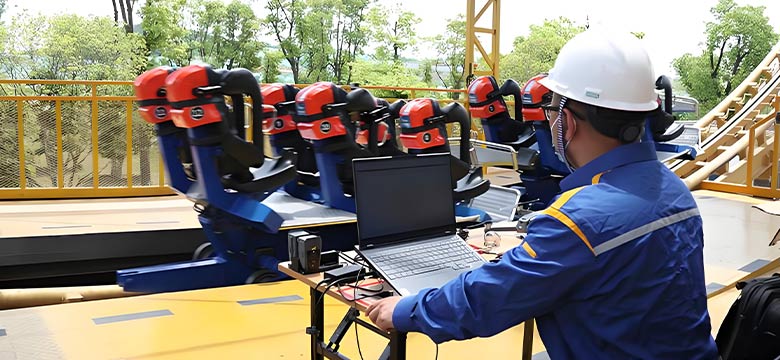 Engineer running roller coaster maintenance checklist with diagnostic laptop system.