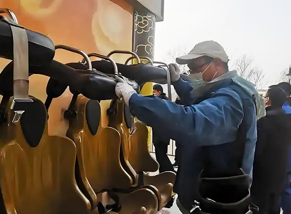 Technician performing daily roller coaster maintenance, checking safety restraints before operation.