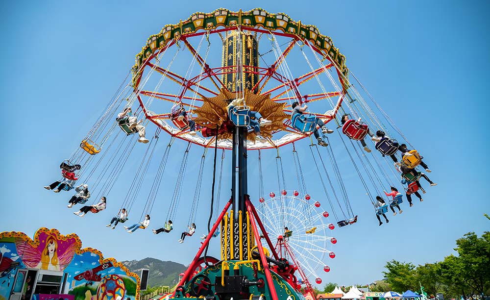 Rotating swing ride with suspended flying chairs spinning at high speed in theme park