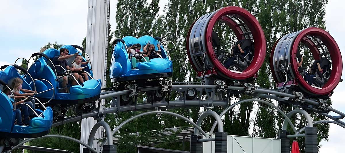 Spinning family backyard roller coaster with rotating blue and red cars on elevated steel track