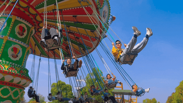 Excited riders enjoying the thrill of a swing ride, experiencing centrifugal force and the sensation of flying in the amusement park.