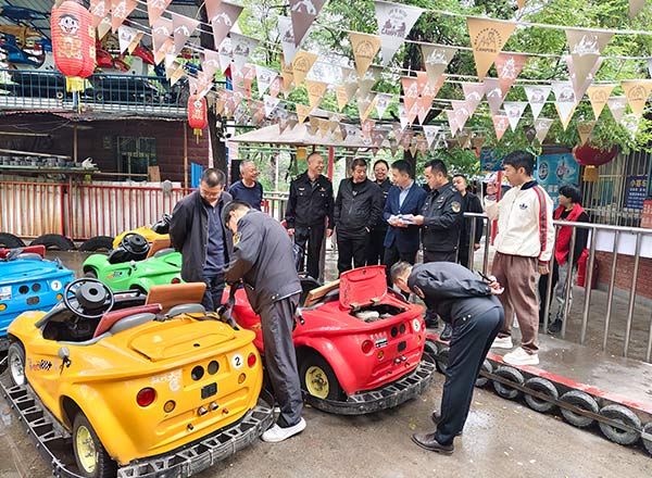 Team of workers performing maintenance on colorful amusement park cars.
