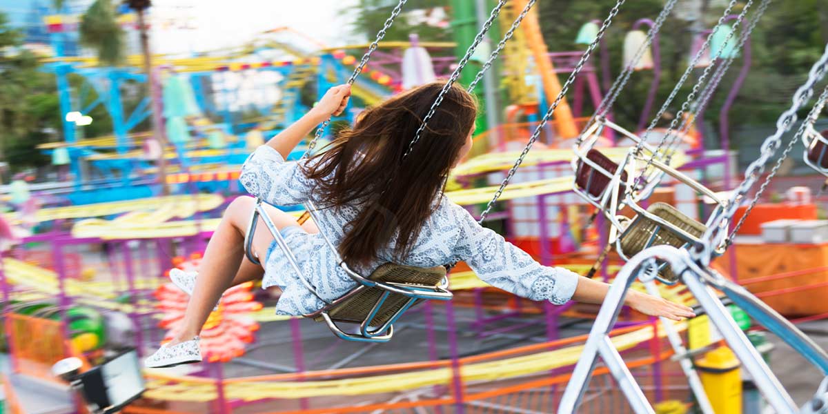 Young woman enjoying a carnival swing ride at an amusement park, highlighting the fun and family-friendly experience.
