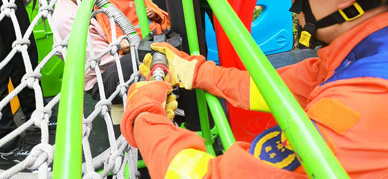 Trabajador del parque de atracciones realizando el mantenimiento de la estructura de la atracción utilizando una escalera y una herramienta eléctrica.