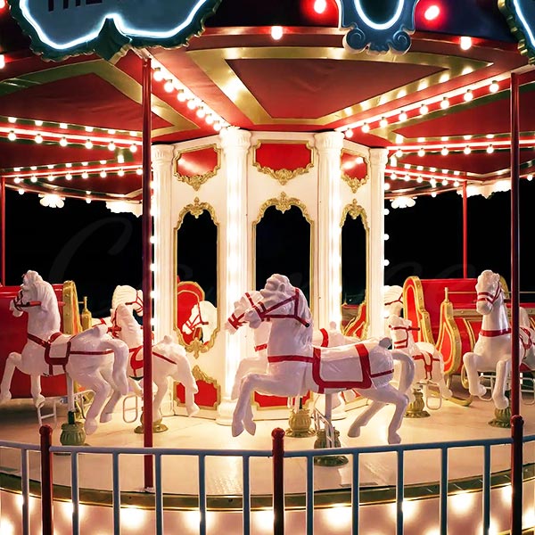 A classic carousel ride with beautifully painted white horses and decorative lighting at night