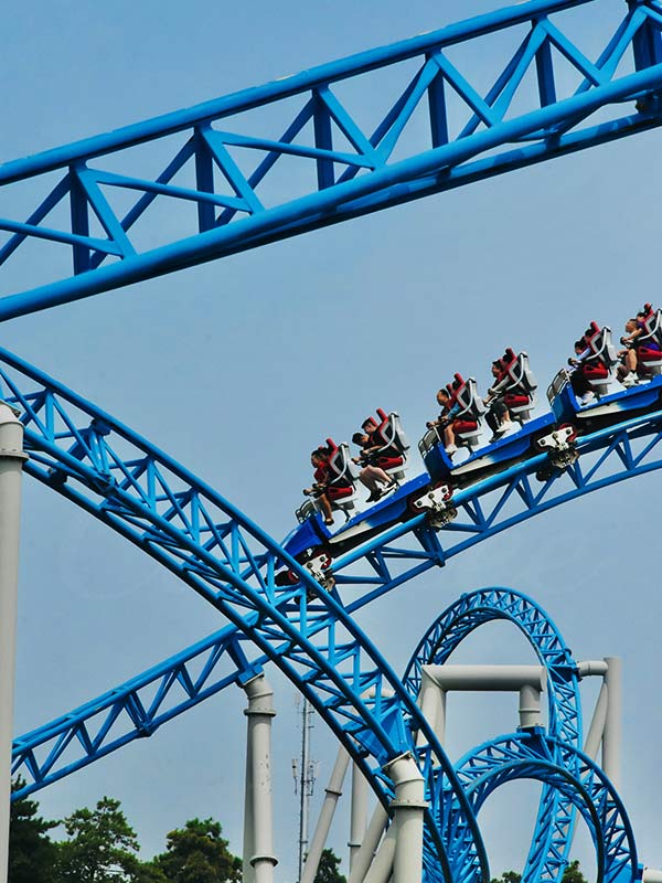 Blue steel family roller coaster with riders enjoying smooth turns, designed and manufactured by Carnee Rides
