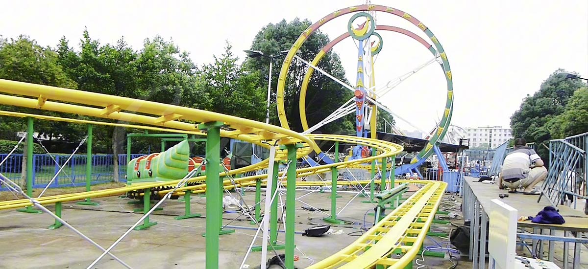 Caterpillar style family roller coaster ride with yellow track and green supports made by Carnee Rides.