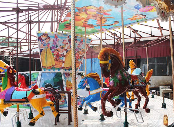 Early stage of double decker carousel rides installation with visible horse figures and decorative elements being assembled