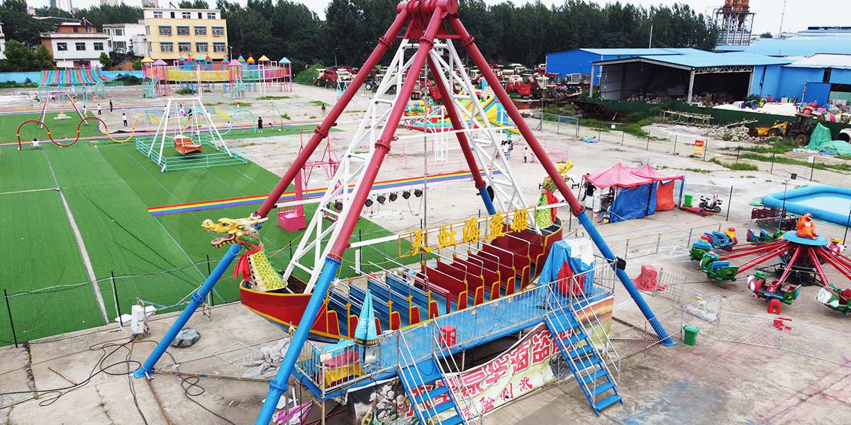 Большой аттракцион на тему пиратского корабля с драконом проходит тестирование на заводе Carnee Rides, готовясь к поставке клиенту парка развлечений.