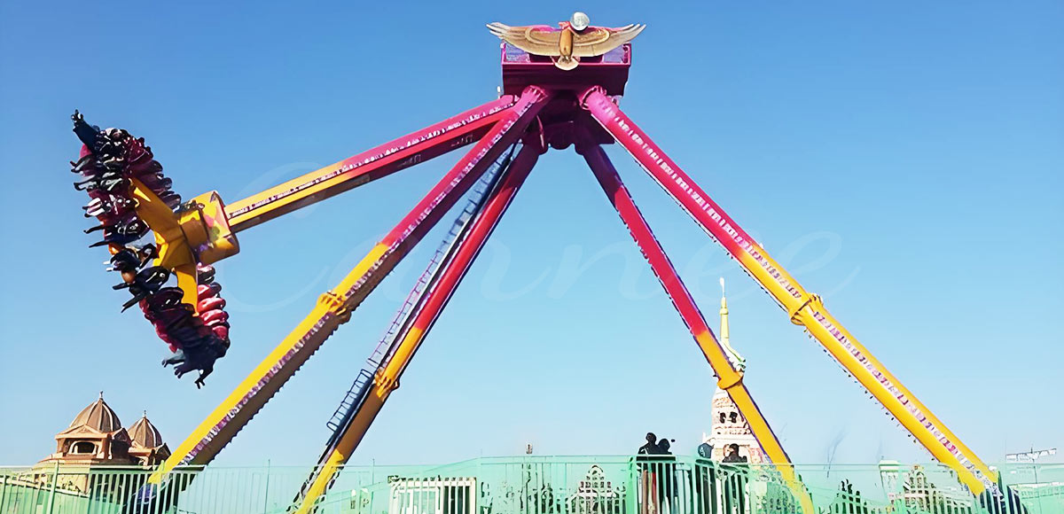 Massive pendulum ride swinging at theme park showing full motion under clear sky.