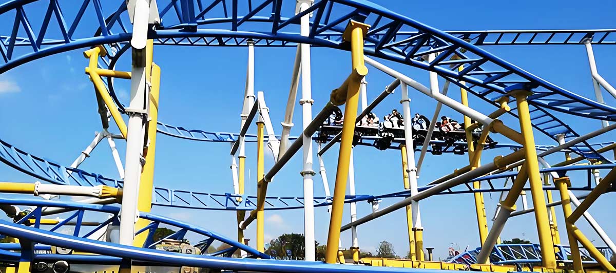 Grandes montagnes russes modernes en acier avec des rails bleus et jaunes conçus pour des virages et des boucles en douceur.