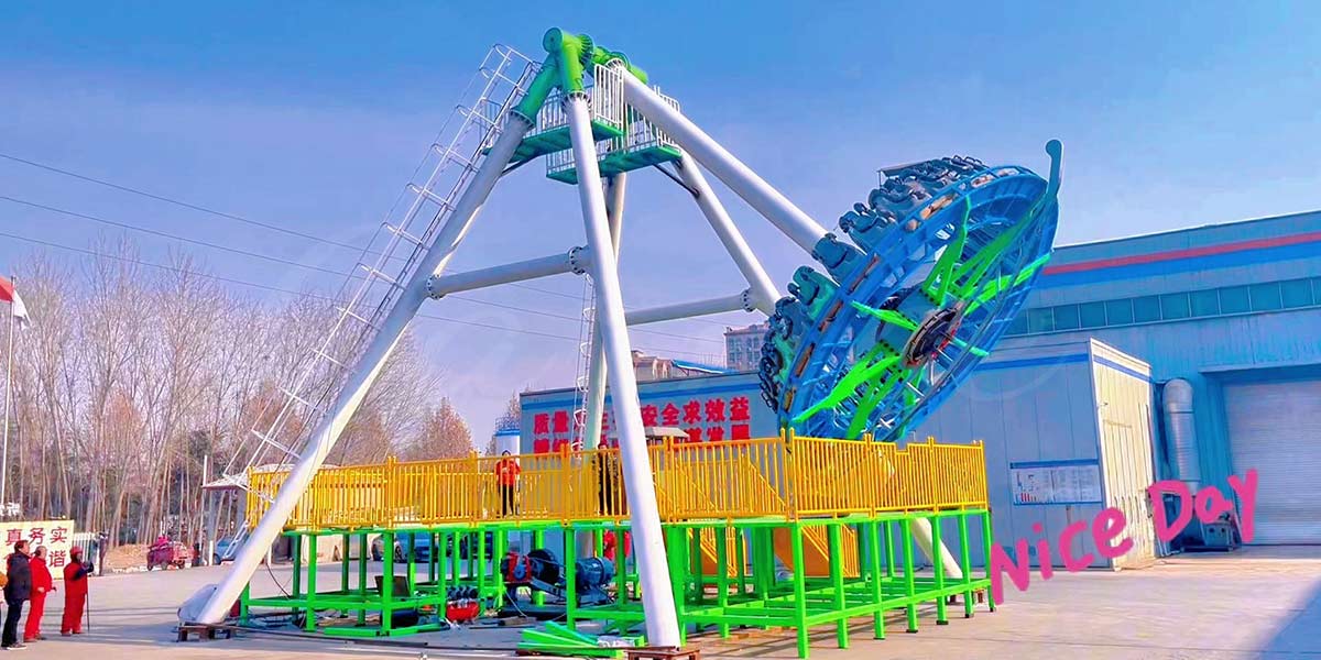 Large pendulum ride installation at factory site showing steel structure and platform setup.
